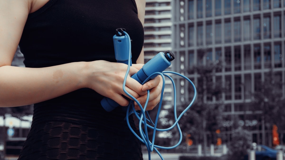 Close-up of a woman holding a blue jump rope, ready for fitness training or a home workout. Concept of healthy lifestyle, sport, activity, and motivation.